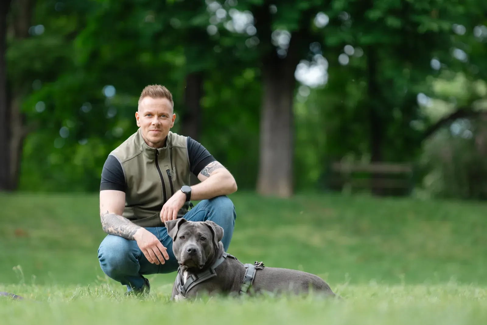 Hundetrainer Steffen Taubitz kniet neben seinem Hund Luna im Park in Graz